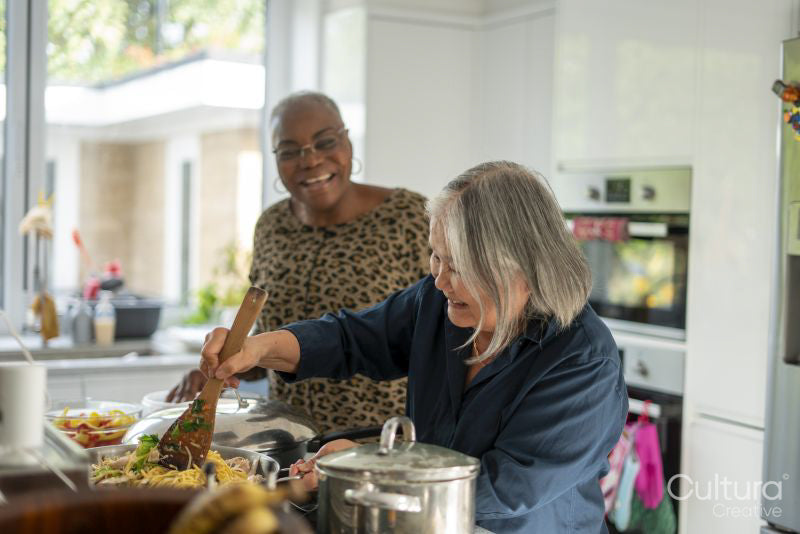 Two senior women preparing meal in kitchen