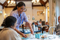 Dietitian serving coffee to group of seniors at cafeteria in nursing home