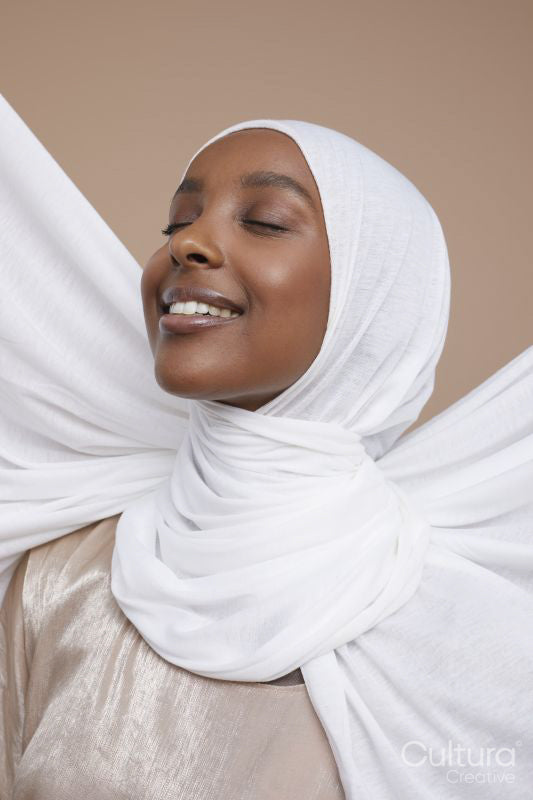 Studio shot of smiling young woman in white hijab