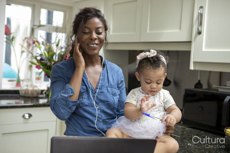 Woman working on laptop at home and taking care of baby daughter