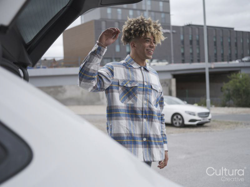 Smiling young man closing car trunk