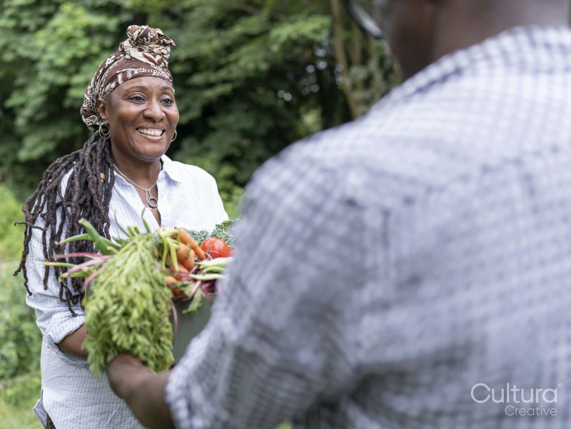 Smiling mature couple holding vegetables from garden