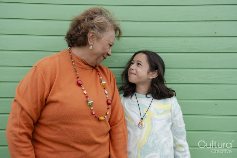 Portrait of grandmother standing with granddaughter against green wall