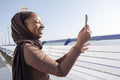 Muslim woman photographing view with smart phone on sunny day