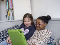 Girl friends using digital tablet at home