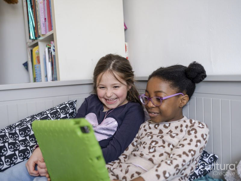 Girl friends using digital tablet at home