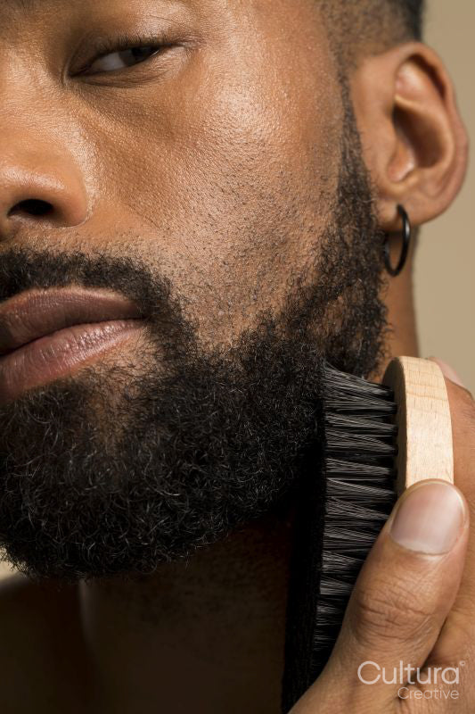 Studio portrait of young man brushing beard