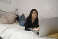 Teenage girl using laptop on bed at home