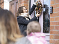 Women holding baby and looking at friend hanging wreath on door