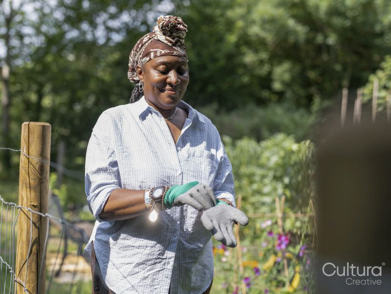 Smiling mature woman putting on gardening gloves