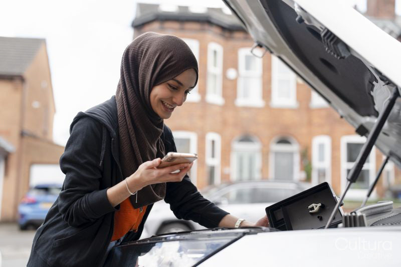 Woman wearing hijab looking into car engine