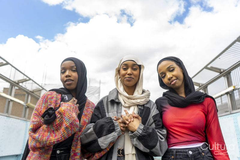 Portrait of smiling young women wearing hijabs holding hands