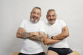 Portrait of two smiling senior men in white t-shirts against gray background