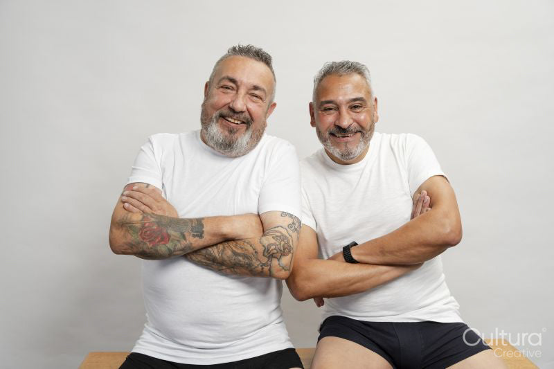 Portrait of two smiling senior men in white t-shirts against gray background