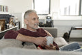 Smiling mature man relaxing on sofa at home
