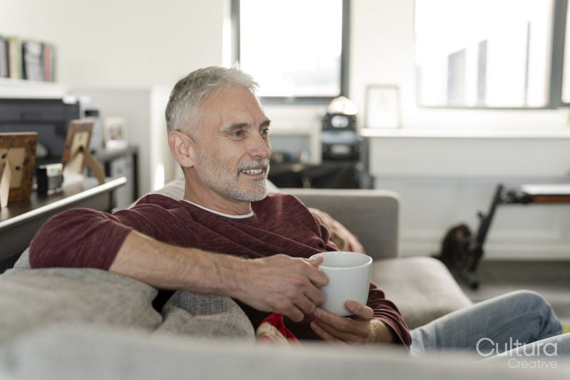 Smiling mature man relaxing on sofa at home