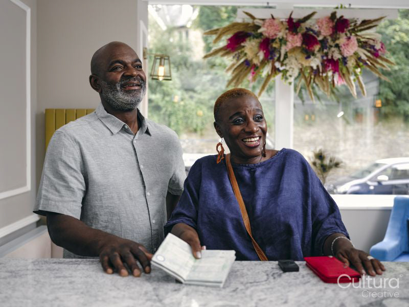 Close-up of mature couple holding passport at hotel front desk