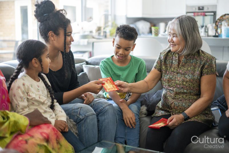 Family gathered in living room, sharing red envelopes