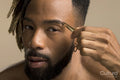Studio portrait of young man with dreadlocks plucking eyebrow