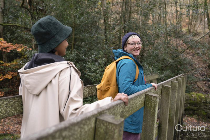 Smiling female hikers on bridge in forest