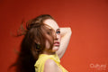 Woman in a yellow dress with windswept hair in a studio