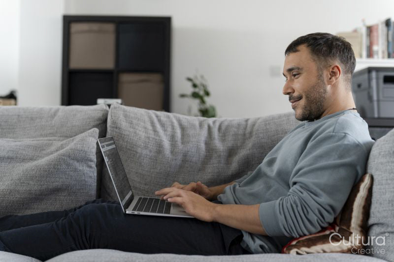 Smiling mature man working on laptop on sofa