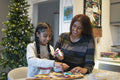 Smiling mother and daughter decorating gingerbread cookies in kitchen