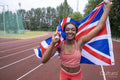 Portrait of smiling athletic woman with British flag on running track