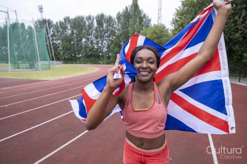 Portrait of smiling athletic woman with British flag on running track