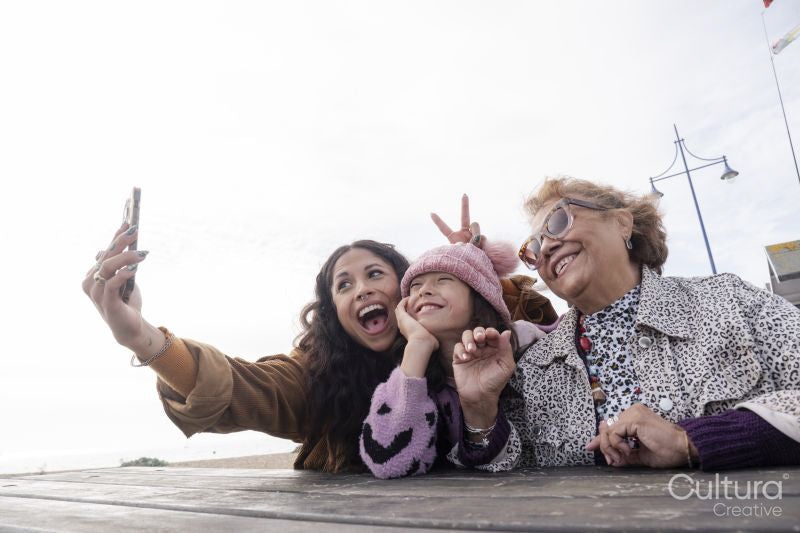 Grandmother, mother and daughter taking selfie with smart phone