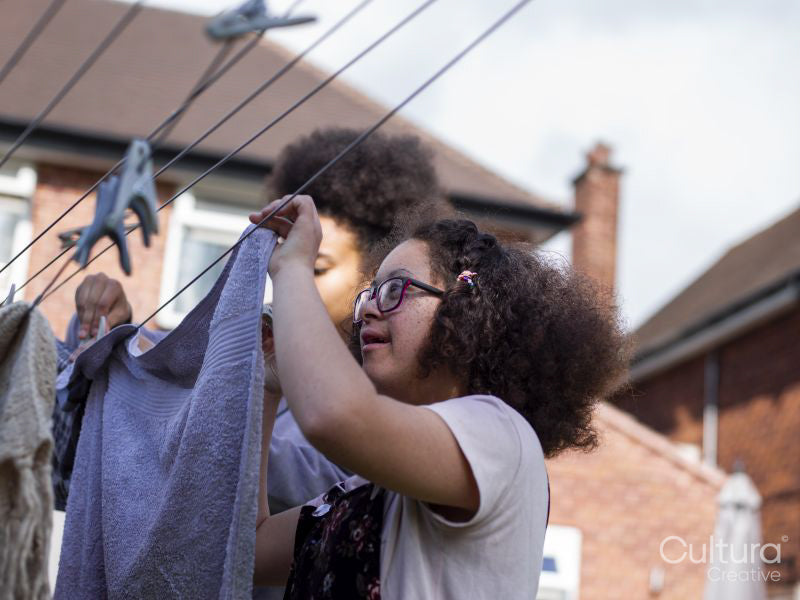 Two girls hanging laundry in backyard