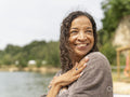 Portrait of smiling woman wrapped in towel by lake