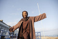 Portrait of smiling Muslim woman standing with arms outstretched on sunny day