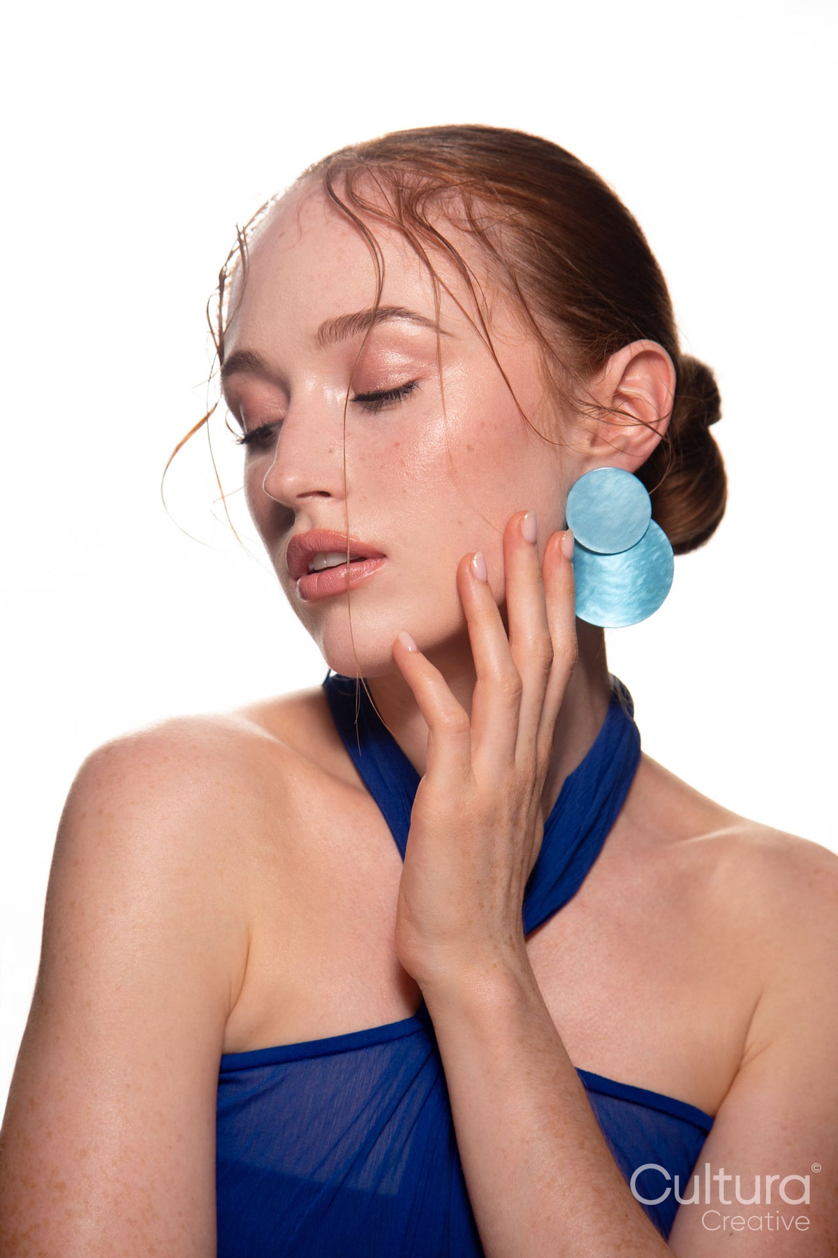 Studio portrait of a woman in a blue dress and large blue earrings