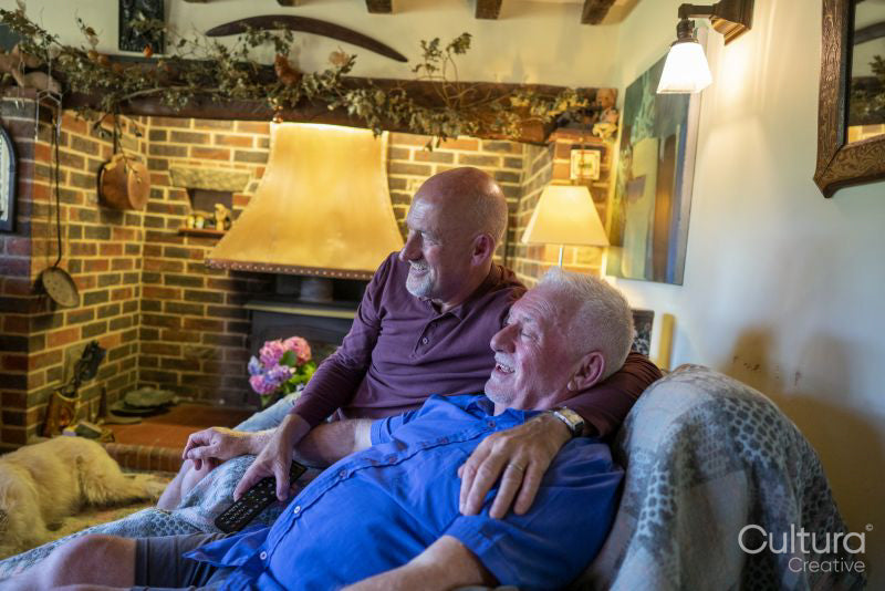 Senior male couple watching TV at home