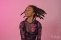 Smiling young woman shaking hair against pink background