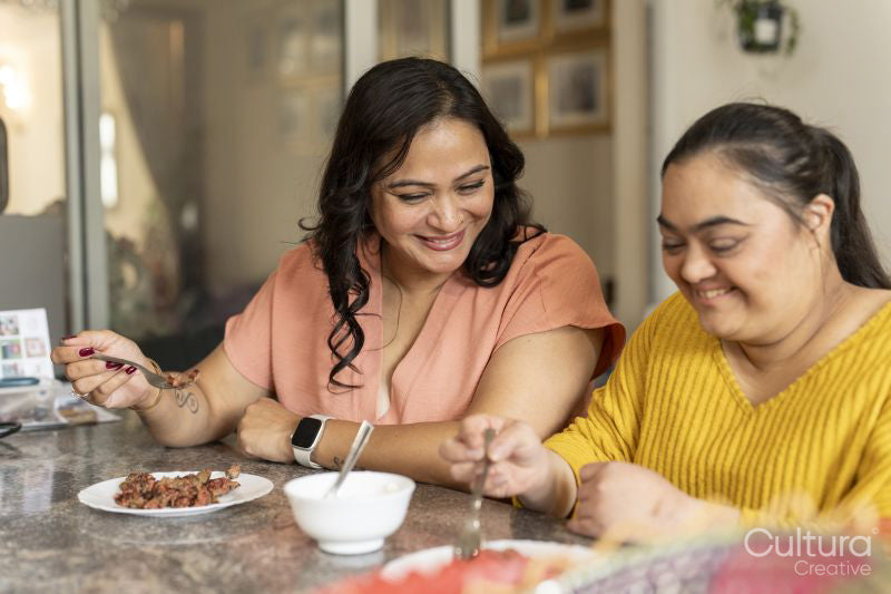 Mother eating dinner with down syndrome daughter at home