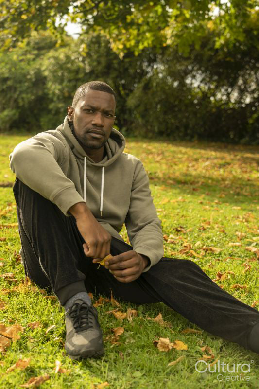 Portrait of man sitting on lawn in park in autumn