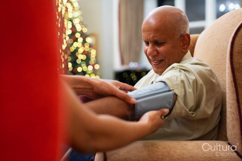 Nursing assistant adjusting blood pressure gauge on senior mans arm in nursing home