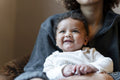 Smiling baby girl sitting on mothers lap