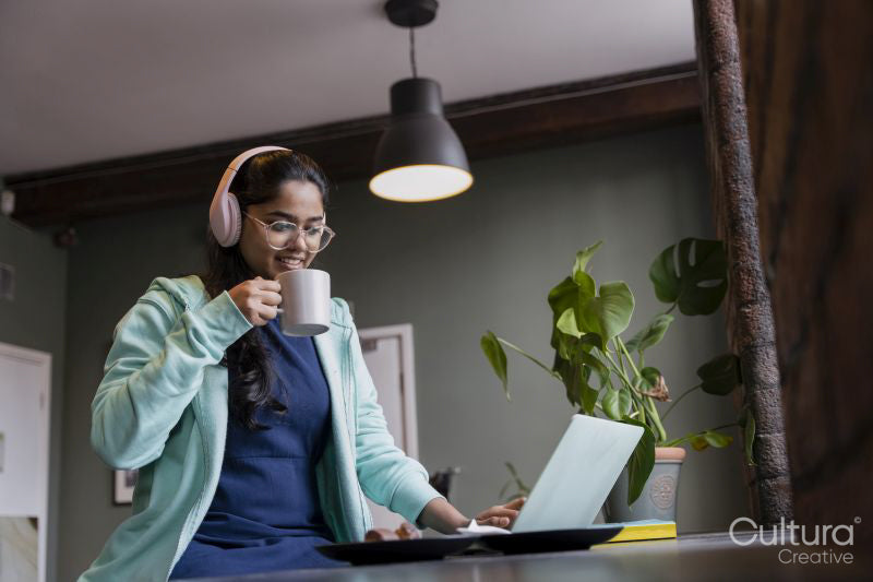 Female student using laptop while studying and drinking tea