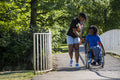 Teenage girl in wheelchair with friend walking in park