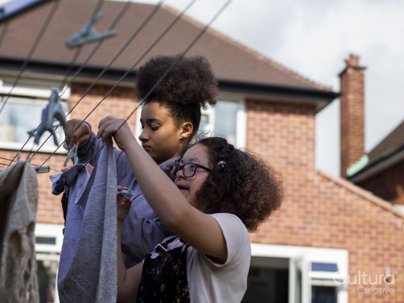 Two girls hanging laundry in backyard