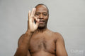 Portrait of smiling man making OK sign against gray background
