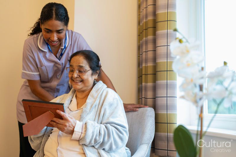 Senior lady showing photography to nurse at nursing home