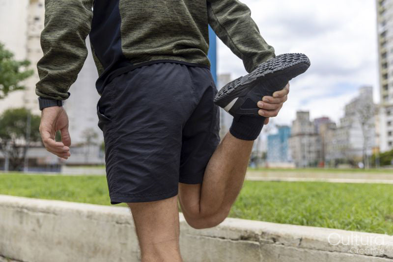 Mid section of man in sports clothing stretching leg in city