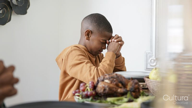 Boy praying before Kwanzaa meal