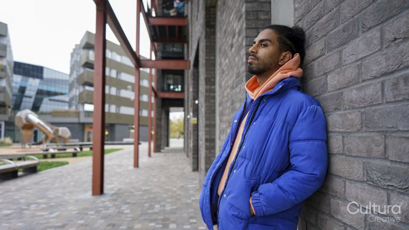 Young man wearing blue puffer jacket leaning on wall