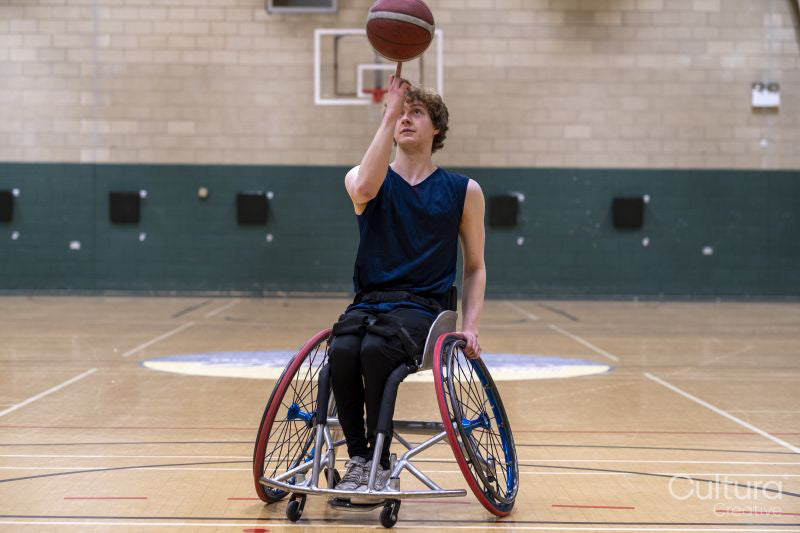 Male basketball player in wheelchair spinning ball
