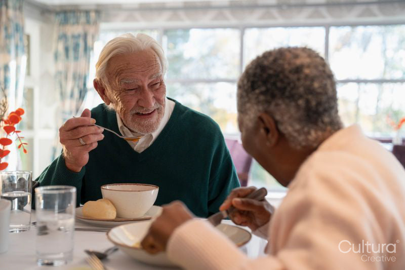 Smiling senior people eating meal in nursing home